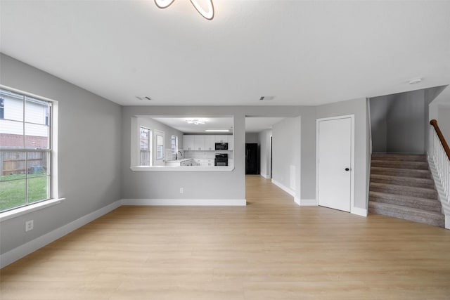 unfurnished living room featuring sink and light hardwood / wood-style floors