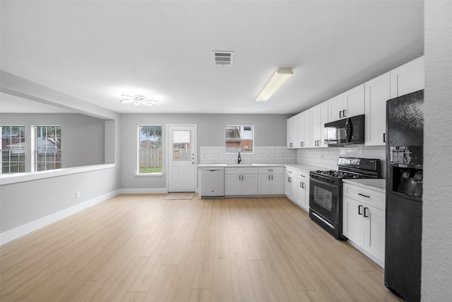 kitchen featuring sink, white cabinetry, tasteful backsplash, light hardwood / wood-style flooring, and black appliances