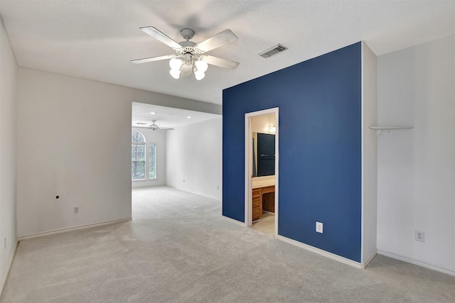 carpeted spare room featuring a textured ceiling, baseboards, ceiling fan, and visible vents