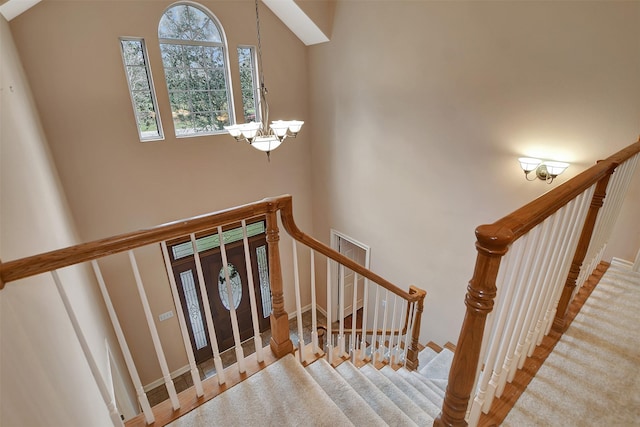 staircase with a high ceiling and a chandelier