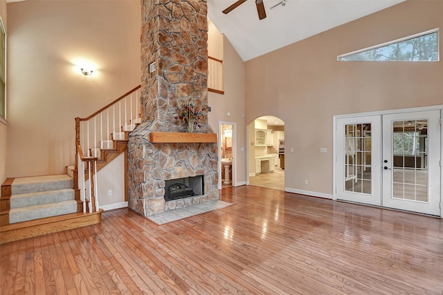 unfurnished living room featuring wood-type flooring, arched walkways, stairs, and ceiling fan