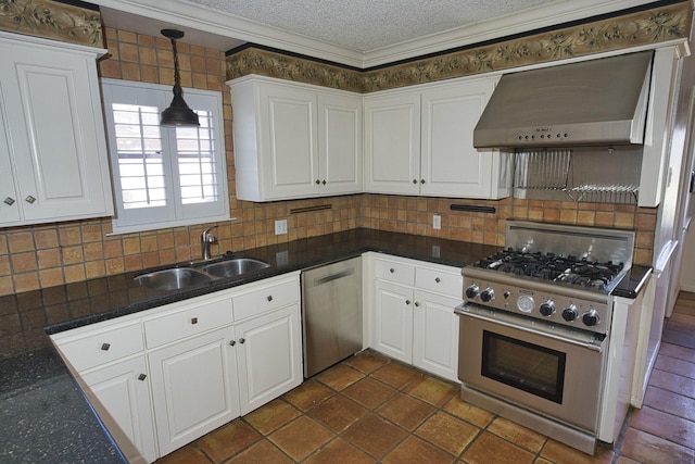 kitchen with wall chimney exhaust hood, sink, hanging light fixtures, stainless steel appliances, and white cabinets