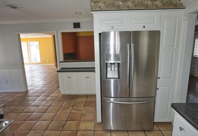 kitchen with ornamental molding, stainless steel fridge, a textured ceiling, and white cabinets