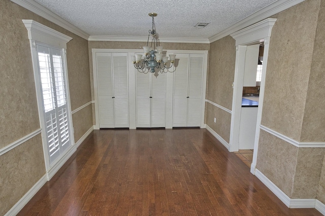 unfurnished dining area featuring an inviting chandelier, dark wood-type flooring, and a textured ceiling