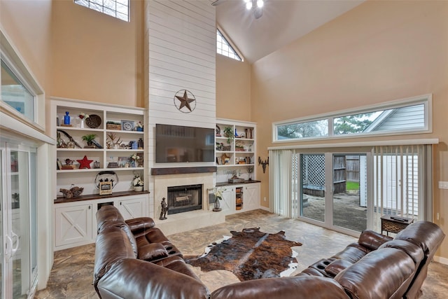 living room with ceiling fan, high vaulted ceiling, a fireplace, and built in shelves