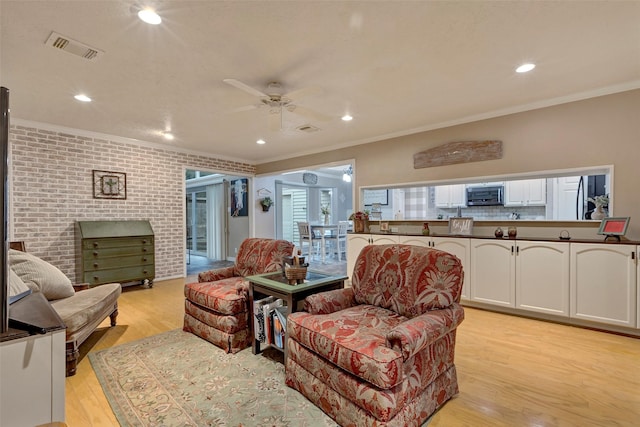 living room with crown molding, light hardwood / wood-style flooring, ceiling fan, and brick wall