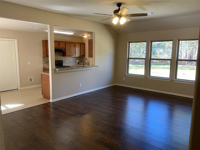 unfurnished living room with ceiling fan, dark hardwood / wood-style floors, and sink