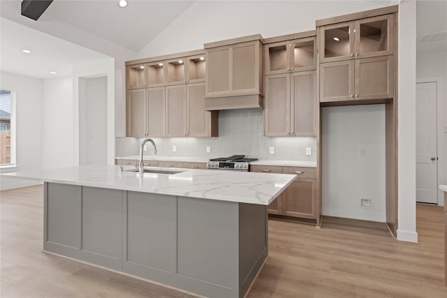 32650 Fly Fish Way, Fulshear, TX 77441 - kitchen with a sink, light wood-type flooring, stainless steel range with gas cooktop, decorative backsplash, and light stone countertops