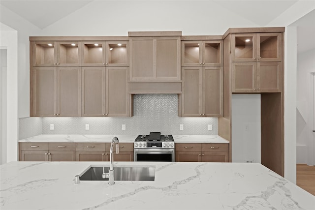 32650 Fly Fish Way, Fulshear, TX 77441 - kitchen featuring stainless steel gas stove, vaulted ceiling, a sink, light stone countertops, and decorative backsplash