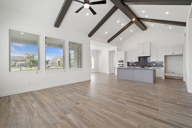 32650 Fly Fish Way, Fulshear, TX 77441 - kitchen featuring open floor plan, beam ceiling, white cabinetry, stainless steel microwave, and decorative backsplash
