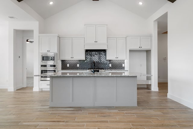 32650 Fly Fish Way, Fulshear, TX 77441 - kitchen featuring stainless steel appliances, white cabinetry, an island with sink, recessed lighting, and high vaulted ceiling