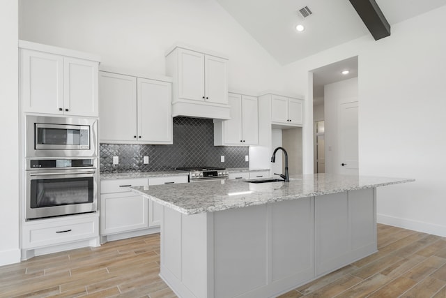 32650 Fly Fish Way, Fulshear, TX 77441 - kitchen with stainless steel appliances, light wood-style flooring, white cabinetry, light stone countertops, and high vaulted ceiling