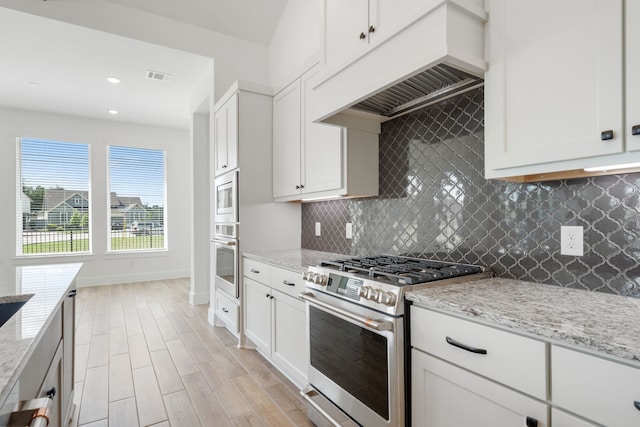 32650 Fly Fish Way, Fulshear, TX 77441 - kitchen with stainless steel appliances, under cabinet range hood, backsplash, light stone counters, and white cabinets