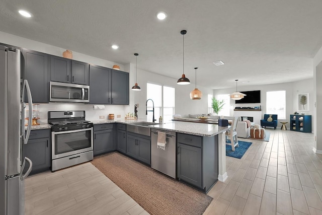 kitchen with stainless steel appliances, decorative light fixtures, kitchen peninsula, and gray cabinetry