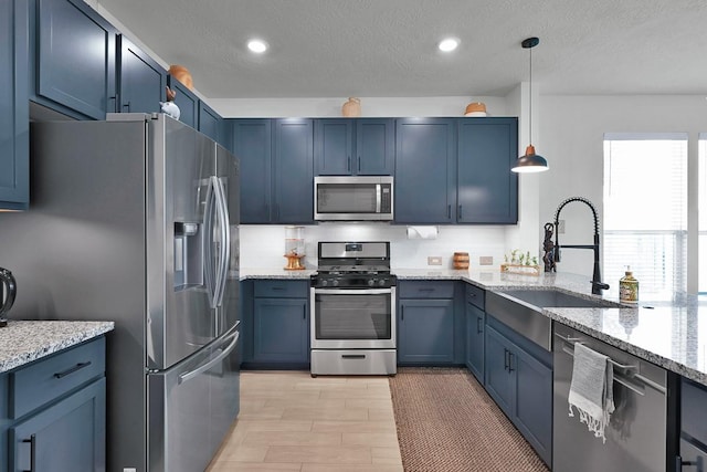 kitchen with tasteful backsplash, sink, hanging light fixtures, stainless steel appliances, and blue cabinetry