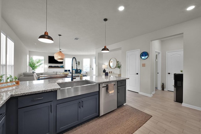 kitchen with light stone counters, dishwasher, sink, and pendant lighting