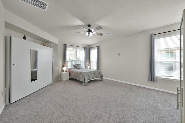 bedroom featuring ceiling fan, light carpet, and a textured ceiling