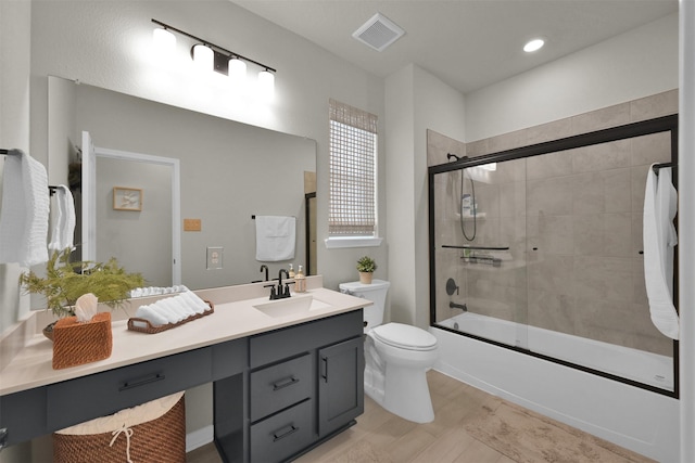 full bathroom with toilet, vanity, and bath / shower combo with glass door