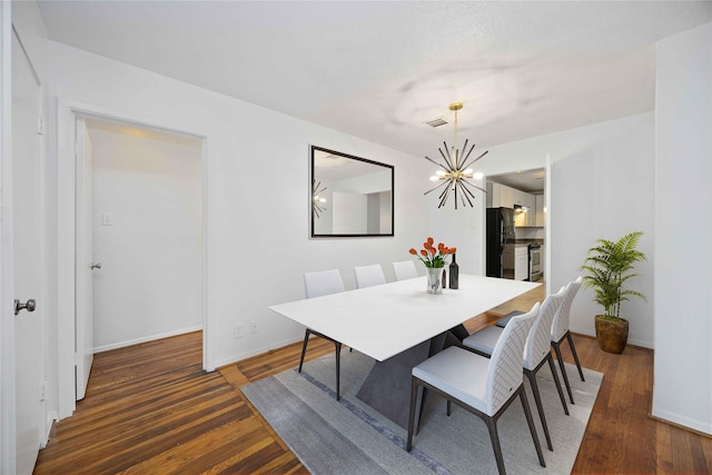 dining room with dark hardwood / wood-style floors and an inviting chandelier