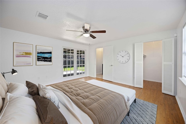 bedroom featuring ceiling fan, a spacious closet, and light hardwood / wood-style floors