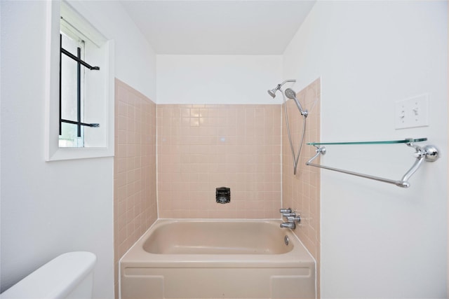 bathroom featuring tiled shower / bath combo and toilet