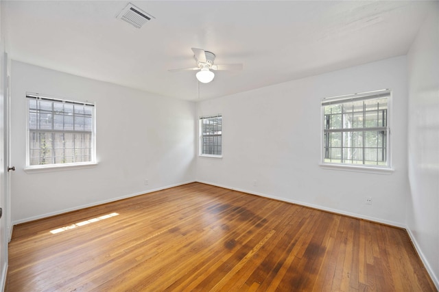 spare room with ceiling fan, hardwood / wood-style flooring, and a wealth of natural light