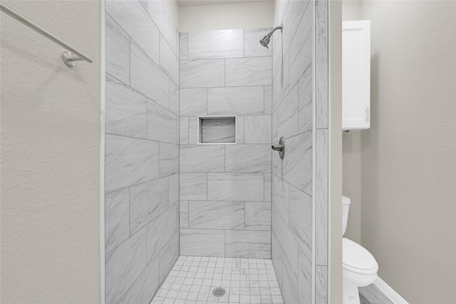 bathroom with toilet and tiled shower