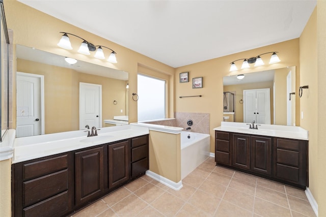 bathroom featuring a garden tub, two vanities, a sink, and tile patterned floors