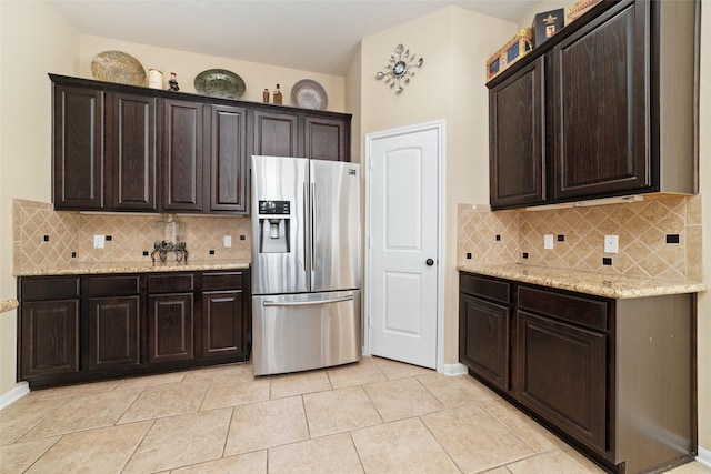 kitchen with light stone counters, stainless steel refrigerator with ice dispenser, and dark brown cabinetry