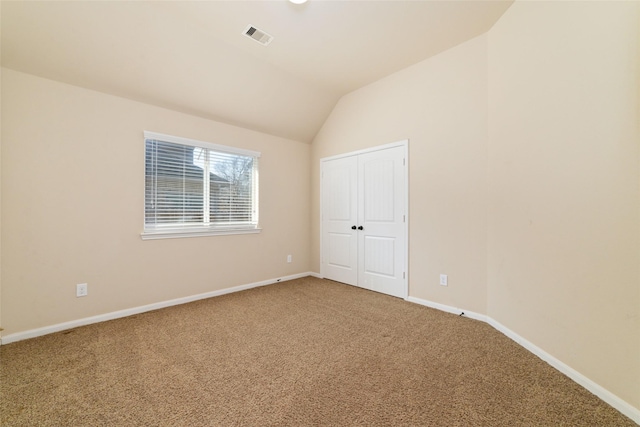 unfurnished bedroom featuring baseboards, visible vents, vaulted ceiling, and carpet flooring