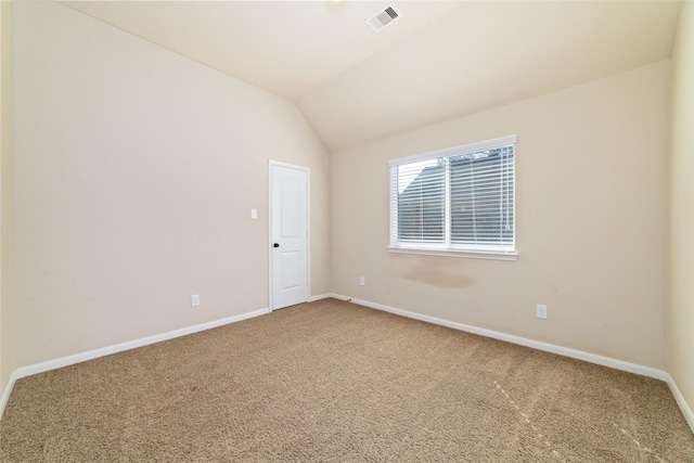 carpeted spare room featuring lofted ceiling, visible vents, and baseboards