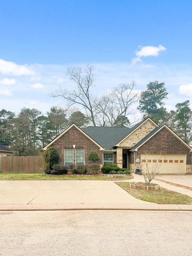 view of front of house featuring a garage, concrete driveway, brick siding, and fence