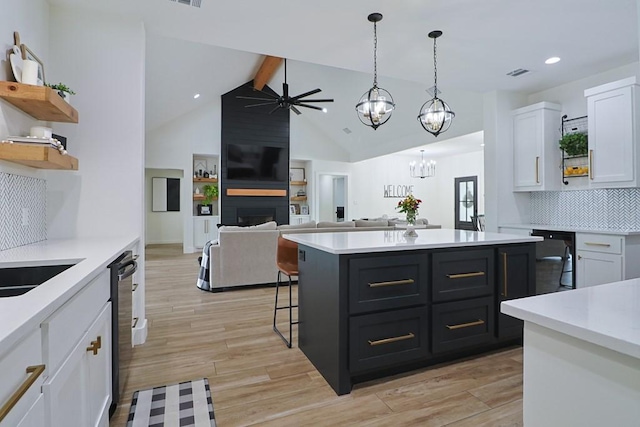 kitchen featuring hanging light fixtures, black dishwasher, a large fireplace, white cabinets, and ceiling fan with notable chandelier