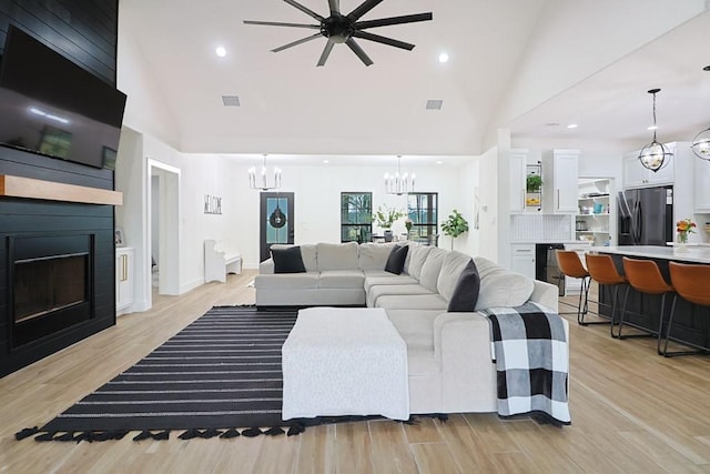 living room with a notable chandelier, beverage cooler, a large fireplace, and light wood-type flooring