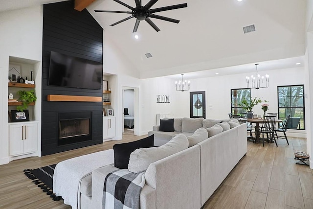 living room with light hardwood / wood-style floors, a large fireplace, and a chandelier