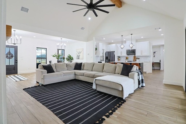 living room featuring beamed ceiling, high vaulted ceiling, ceiling fan with notable chandelier, and light wood-type flooring