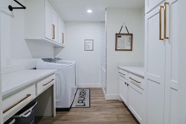 washroom with independent washer and dryer, light hardwood / wood-style flooring, and cabinets