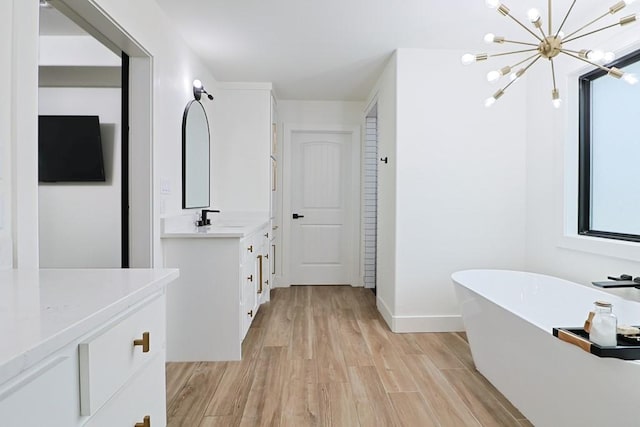 bathroom with an inviting chandelier, vanity, hardwood / wood-style floors, and a bathtub