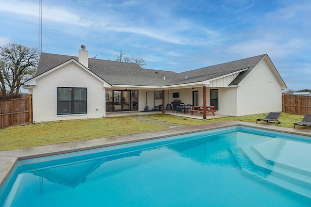 rear view of property with a fenced in pool, a patio, and a yard