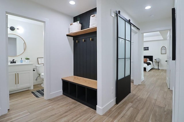 mudroom with a barn door and light wood-type flooring