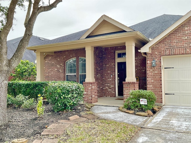 view of front of house featuring a garage, brick siding, and a shingled roof