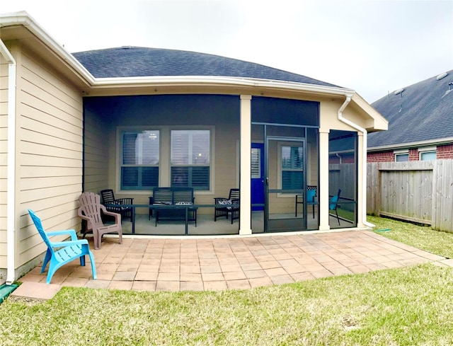 rear view of property featuring a shingled roof, a patio area, fence, and a sunroom