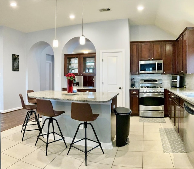 kitchen with light stone countertops, a kitchen island, and appliances with stainless steel finishes