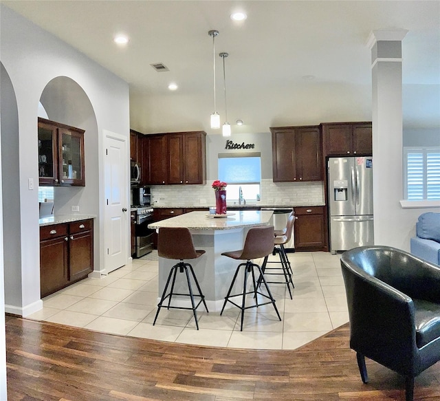 kitchen with light tile patterned floors, visible vents, appliances with stainless steel finishes, and a center island