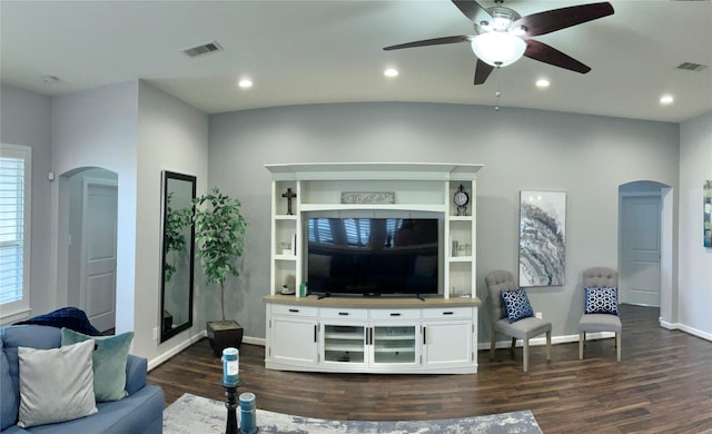 living room with dark wood-style floors, arched walkways, visible vents, and recessed lighting