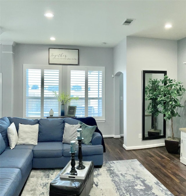 living room with arched walkways, dark wood-style flooring, visible vents, and recessed lighting