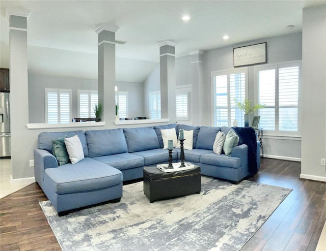 living room with dark wood-type flooring, lofted ceiling, baseboards, and ornate columns