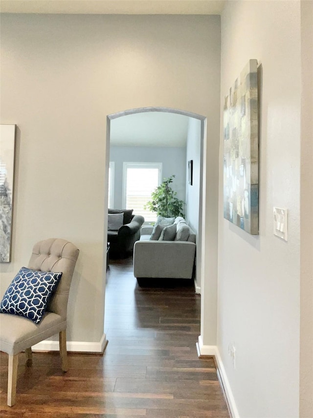 corridor with baseboards, arched walkways, and dark wood finished floors