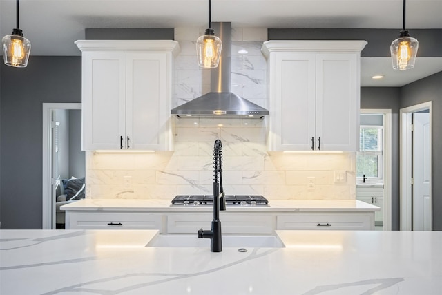 kitchen featuring white cabinets, stainless steel gas stovetop, decorative light fixtures, and wall chimney exhaust hood