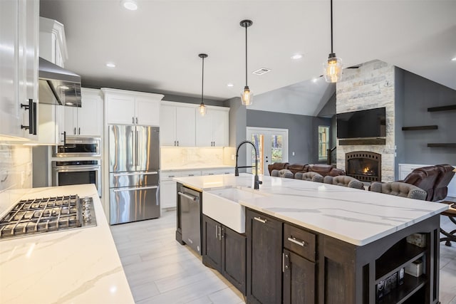 kitchen featuring white cabinets, stainless steel appliances, a sink, and open floor plan